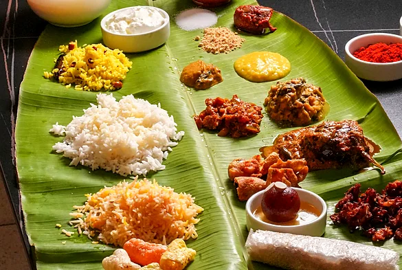 Banana-leaf thali with rice, curries, vegetable dishes, fried snacks and sweets