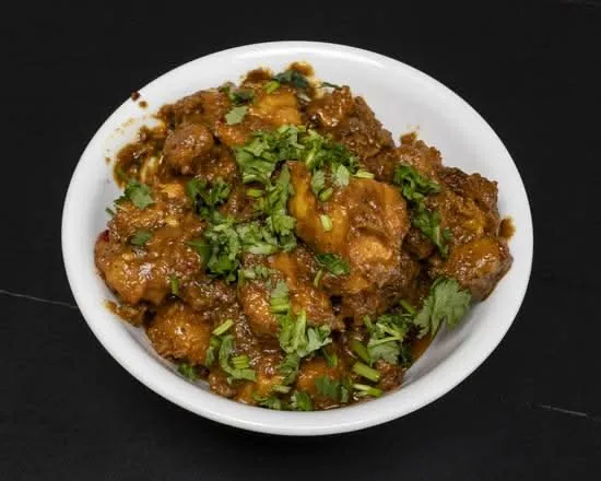 Bowl of Guntur chicken in spicy dark masala topped with chopped coriander